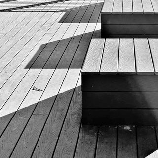 Wooden benches casting shadows on a wooden patio