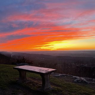 A cement bench overlooking a sunset valley